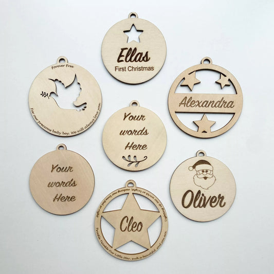 Seven laser-cut wooden Christmas decorations engraved with names including Ella's First Christmas, Alexandra, Oliver and Cleo